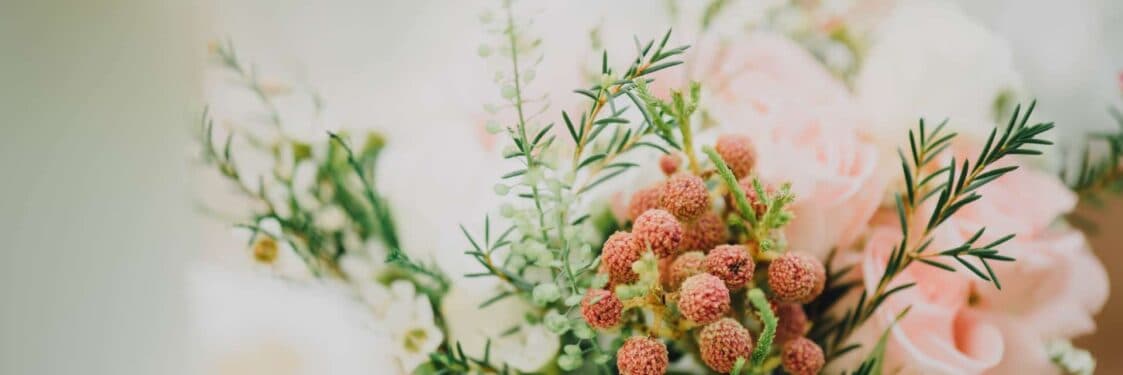A close-up of a floral arrangement featuring pink roses and green foliage.