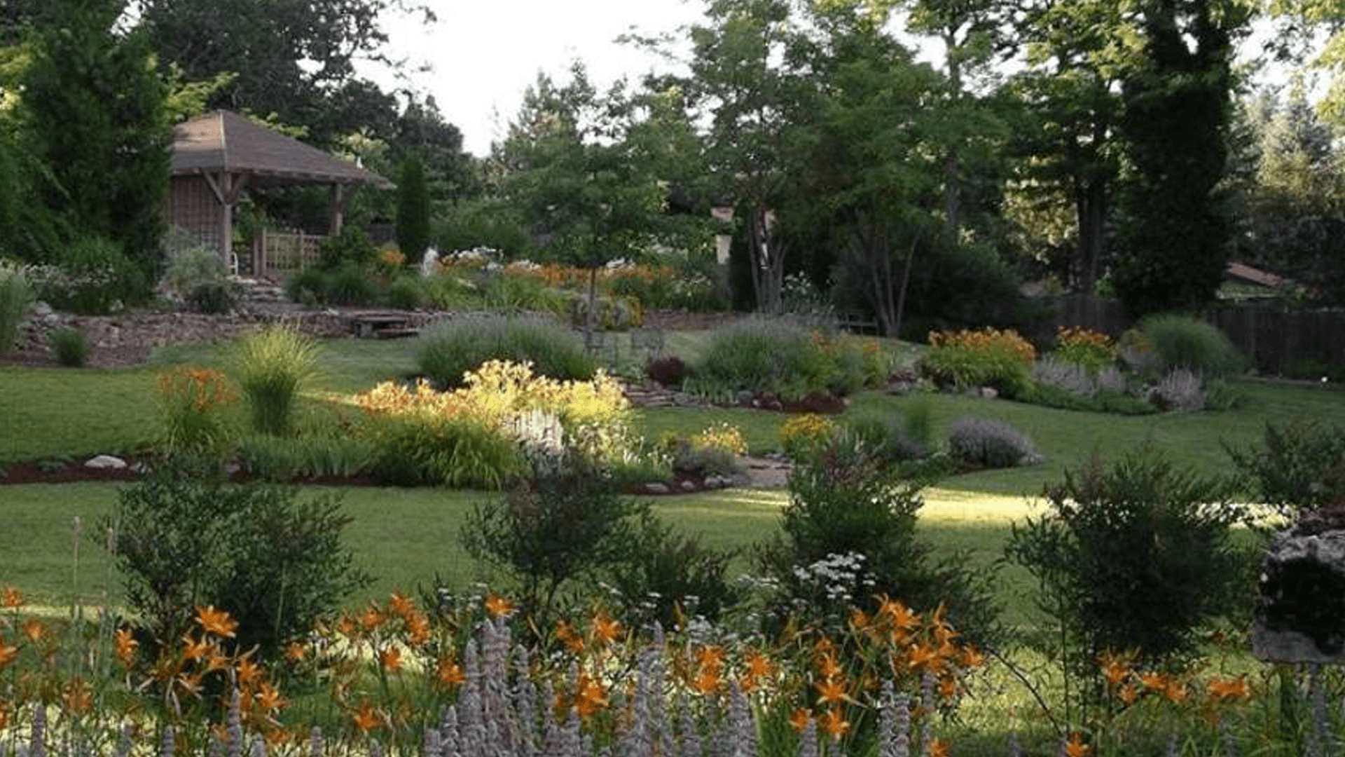 A scenic garden featuring vibrant flowers and a gazebo surrounded by lush greenery.