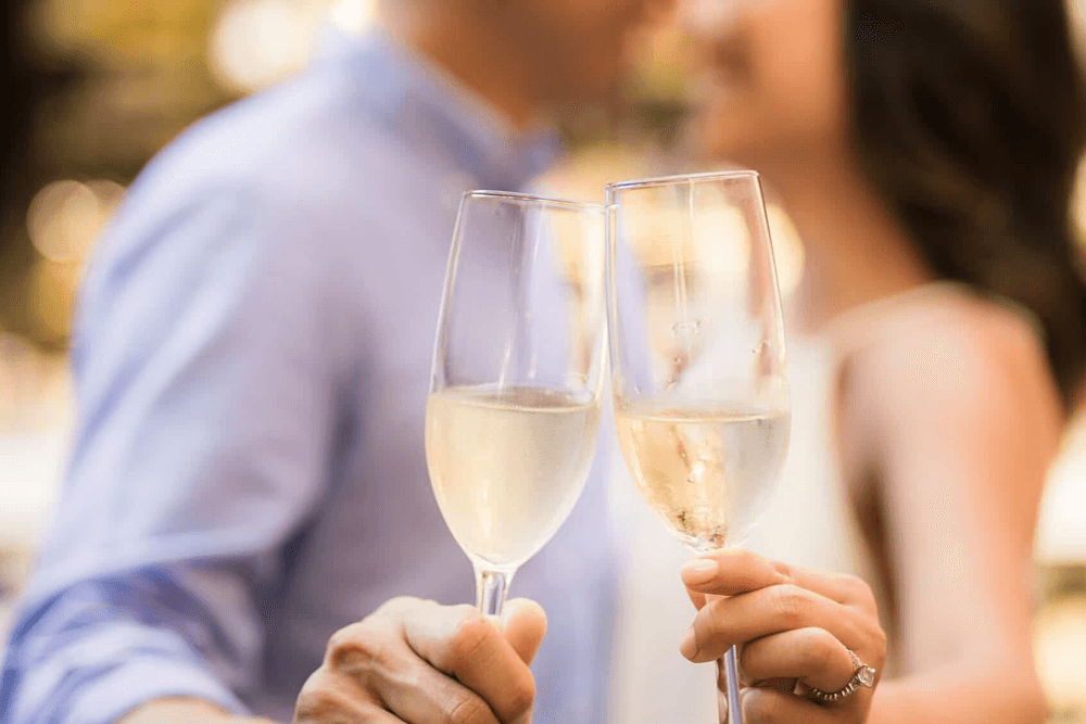 A couple clinks champagne flutes in a celebration.