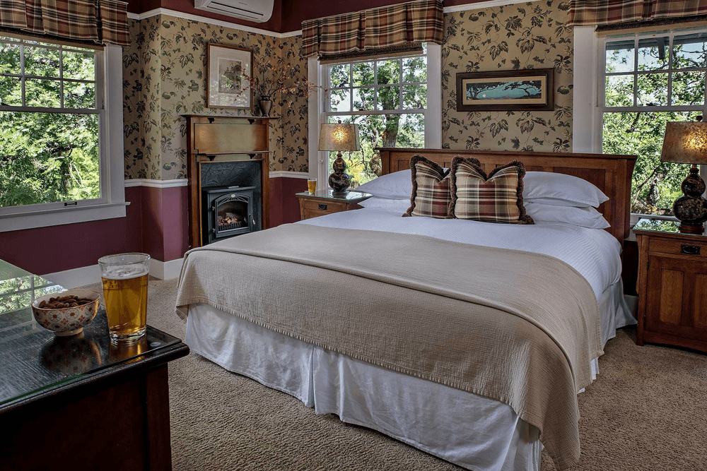 A cozy bedroom with a neatly made bed, two lamps, and a glass of beer on a side table.